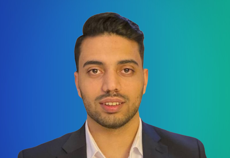 Professional headshot of a person in a suit with a gradient blue to green background.