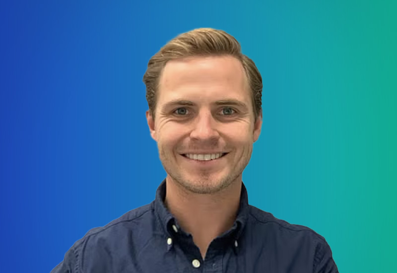 Professional headshot of a smiling man in a blue shirt on a blue and green gradient background, used for AWS Stockholm 2025 event materials.