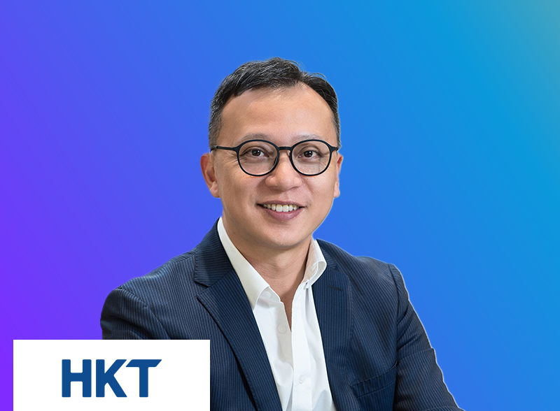 A portrait of a person in business attire wearing glasses, with a blue gradient background and the HKT logo in the lower left corner.