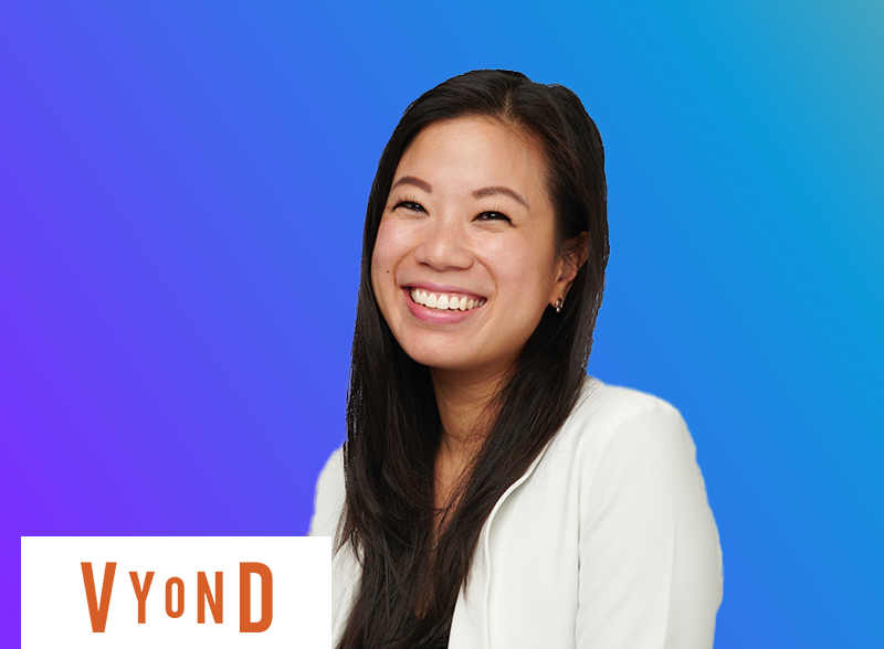 A smiling woman in a white blazer in front of a blue gradient background, with the Vyond logo in the corner.