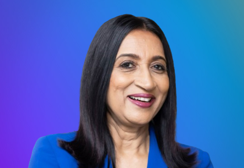 A professional headshot of a smiling person with straight black hair, wearing a blue outfit, on a blue to purple gradient background.