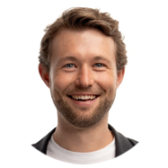 2A person with short, wavy brown hair wearing a white shirt and black jacket.