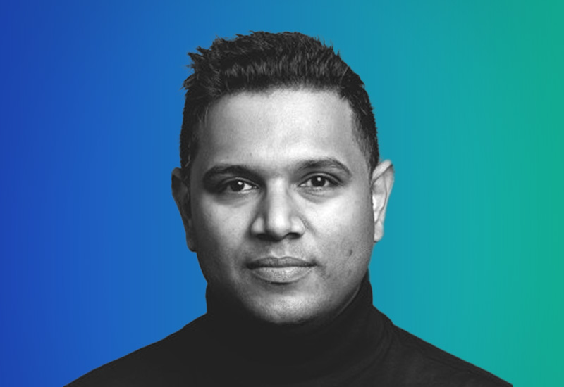 Black and white professional headshot of a person with a short hairstyle and neutral expression, set against a smooth gradient blue to green background.