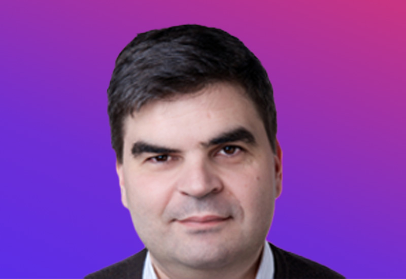 A person with dark hair against a gradient background of purple and pink.