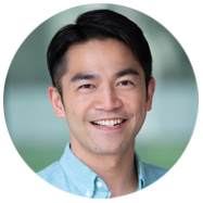 2A person wearing a light blue collared shirt with a blurred background.