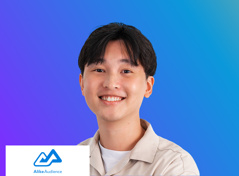 A young person smiles at the camera in front of a blue and purple gradient background, with the AlikeAudience logo in the lower left corner.