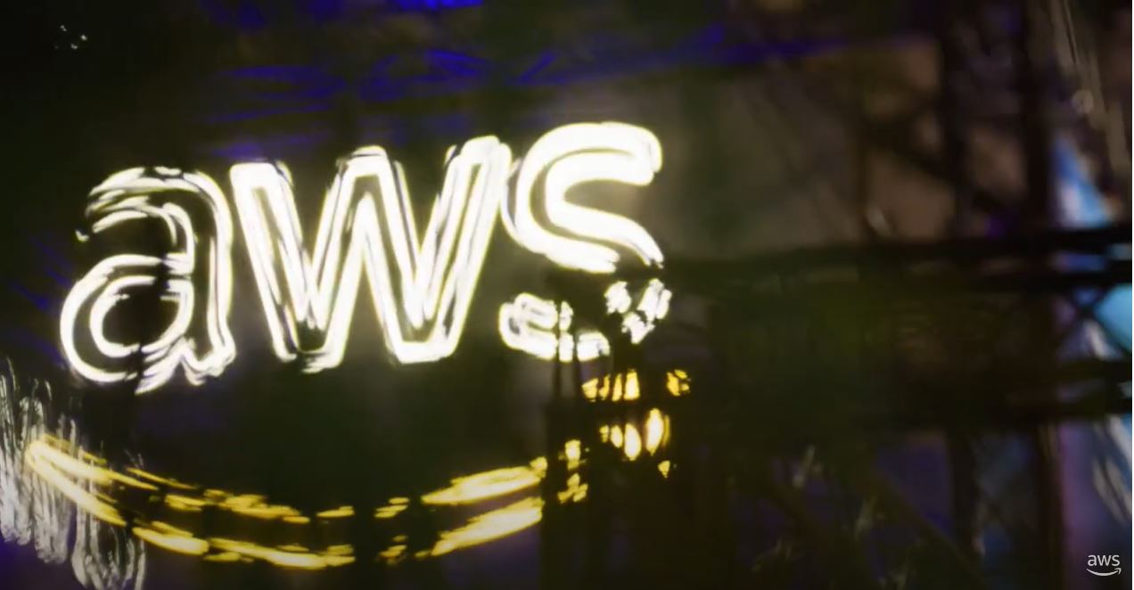 A blurred image of the AWS logo in bright neon lights, featuring a glowing effect and abstract background.