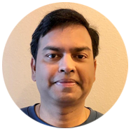 2A person with short black hair wearing a blue shirt against a beige background.