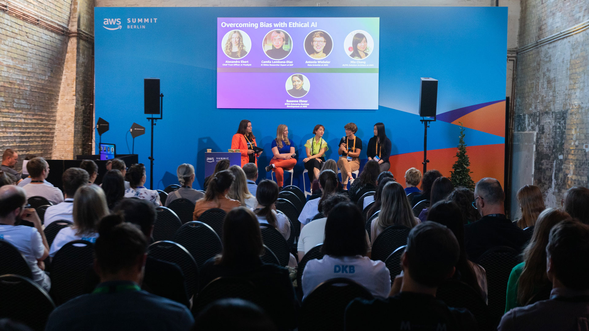 Panel discussion on "Overcoming Bias with Ethical AI" at AWS Summit Berlin, with an audience seated in a brick-walled venue.