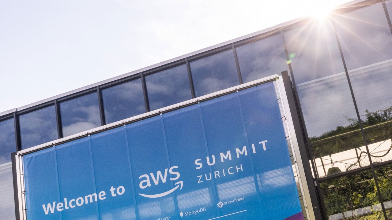 "Banner reading 'Welcome to AWS Summit Zurich' in front of a modern glass building with sunlight shining through."