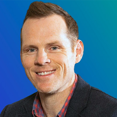 A person wearing a dark blazer over a red and blue checkered shirt, set against a blue gradient background.