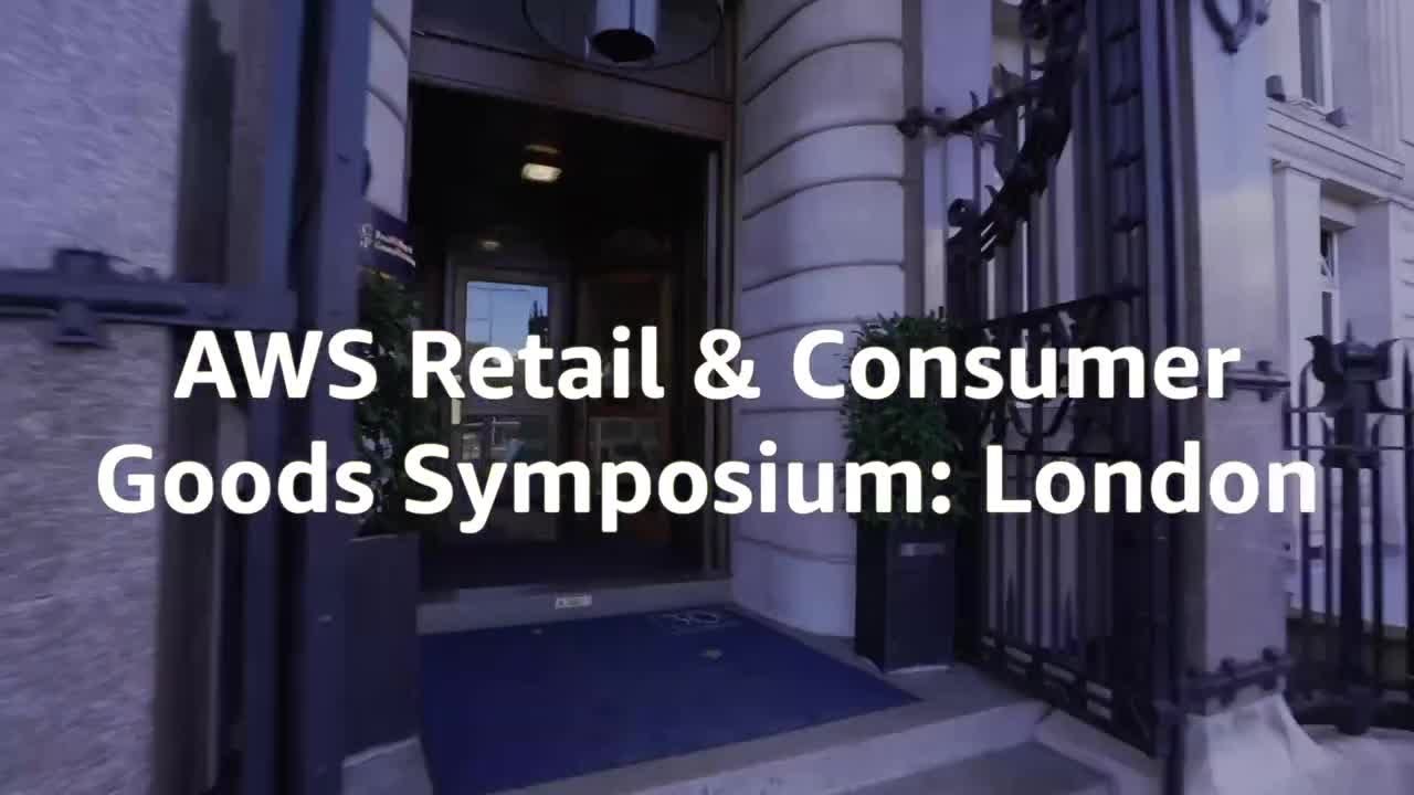 "Entrance to a building with text overlay reading 'AWS Retail & Consumer Goods Symposium: London'."