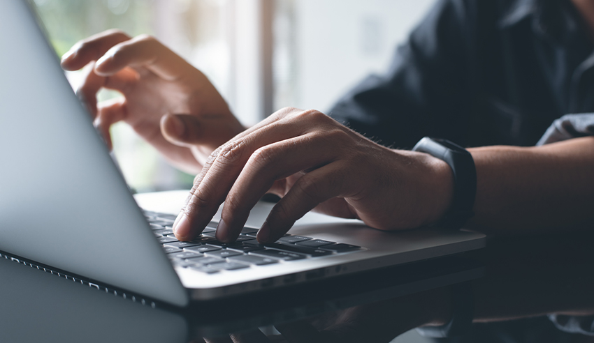 Close-up of hands typing on a laptop keyboard, representing training, certification, or online learning activities.