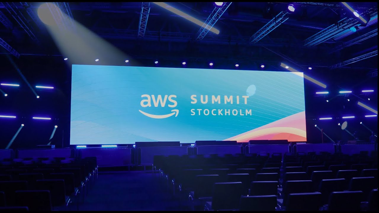 Large event stage with seating and a giant display screen showing 'AWS Summit Stockholm' at the AWS Summit in Stockholm, featuring professional lighting and an auditorium atmosphere.