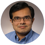 2Man wearing a blue striped collared shirt against a neutral background.