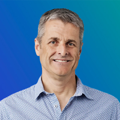 A person wearing a blue patterned shirt against a gradient blue background.