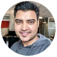 2A person wearing a gray hoodie in a modern office setting with desks and partitions.