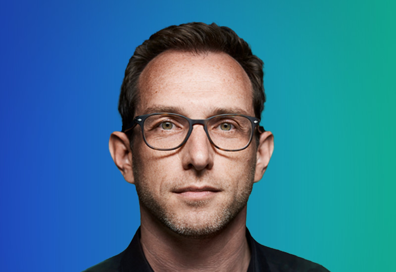 A person with short brown hair against a gradient blue-to-green background.