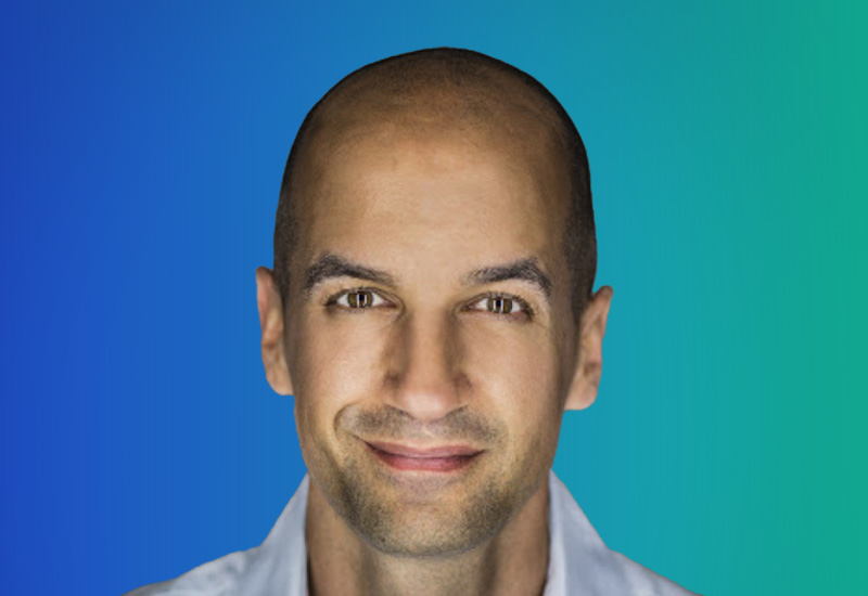 A person with a shaved head against a gradient blue and green background.