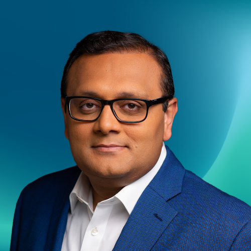 Portrait photo of an AWS Enterprise Strategist wearing glasses and a blue suit jacket, with a gradient blue background.