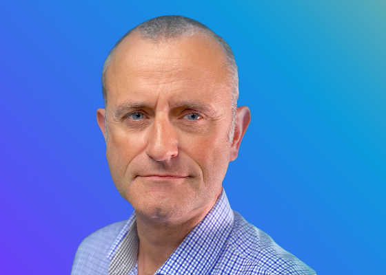 A person wearing a checkered shirt against a gradient blue and purple background.
