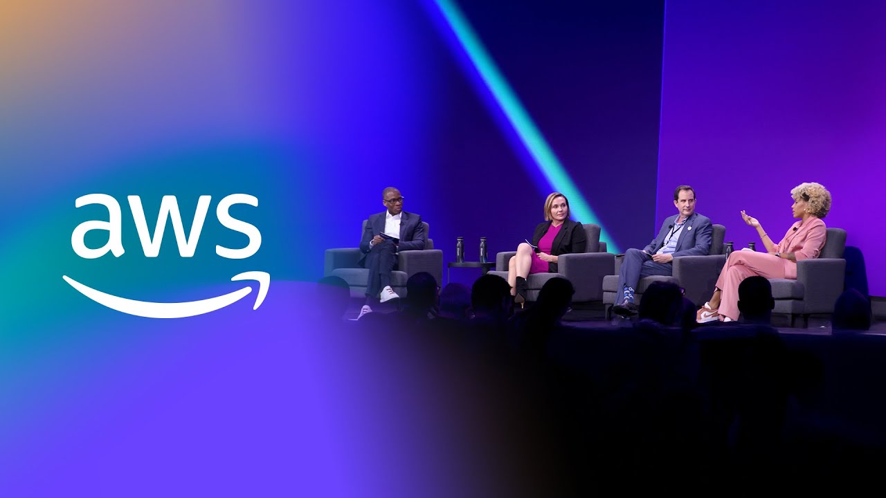 Panel discussion on stage with four seated individuals against a vibrant purple and blue backdrop featuring the AWS logo.