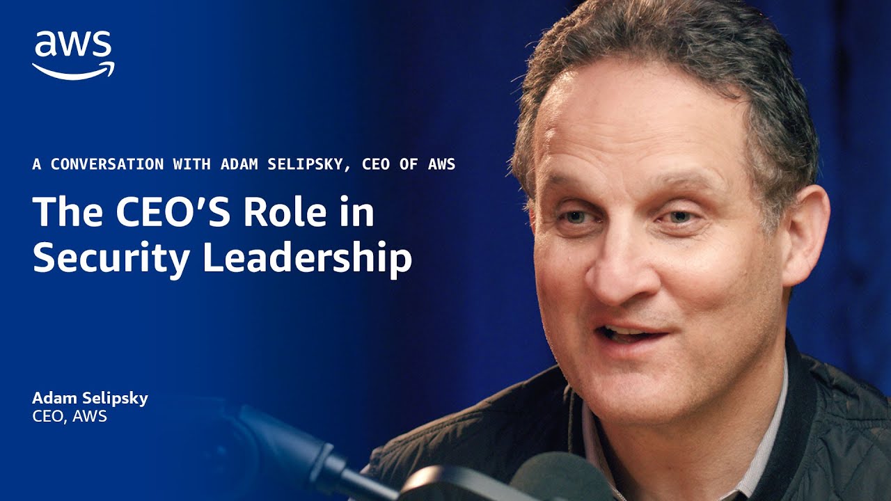 Text on a blue background reads "A conversation with Adam Selipsky, CEO of AWS: The CEO's Role in Security Leadership," with a microphone visible in the foreground.