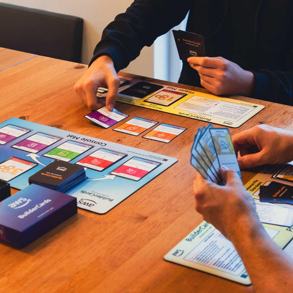 Coworkers playing the AWS BuilderCards board game together, using cards and mats to foster teamwork and social bonding in 2024.