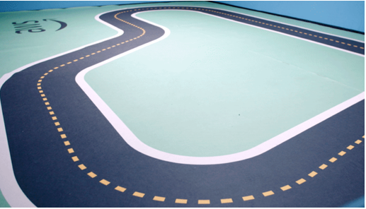 Top-down view of an AWS DeepRacer track with black road, yellow dashed lines, and light green center area.