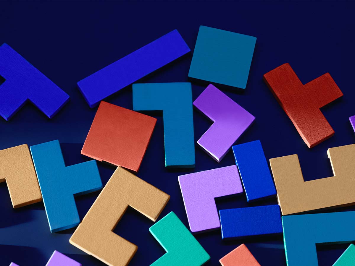 Colorful wooden Tetris-like shapes scattered on a dark blue surface.