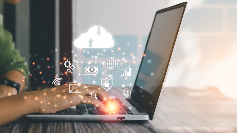 A person typing on a laptop with digital icons representing cloud computing, email, finance, security, and data analytics, symbolizing modern technology and cloud services.