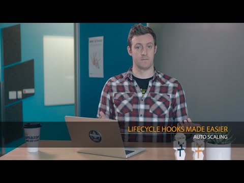 A person sits at a desk with a laptop, presenting a tutorial about making Auto Scaling lifecycle hooks easier. The text 'LIFECYCLE HOOKS MADE EASIER - AUTO SCALING' is overlaid on the image.