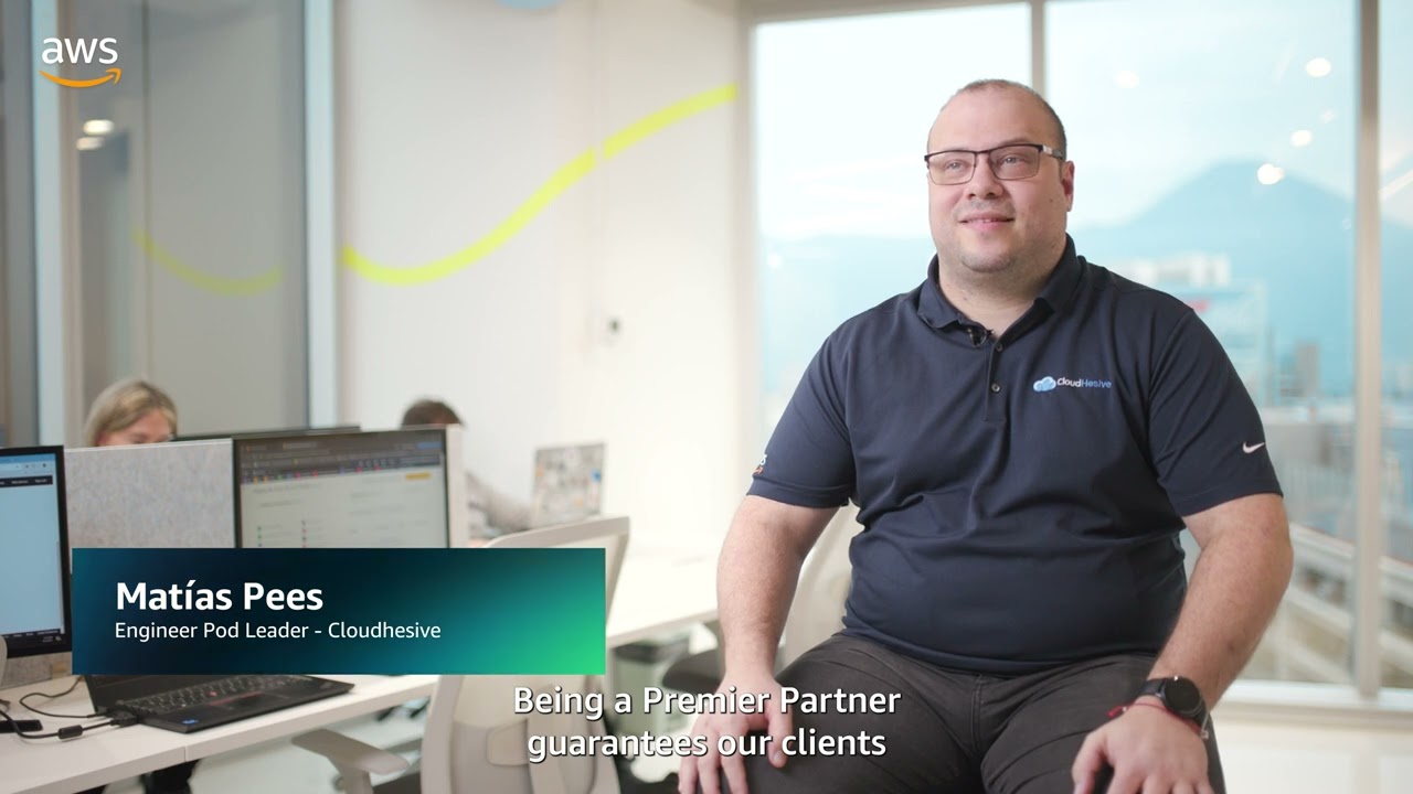 YouTube video thumbnail showing Matías Pees, Engineer Pod Leader at Cloudhesive, during an AWS interview in a modern office setting, with text highlighting his role and discussing AWS Premier Partner guarantees.