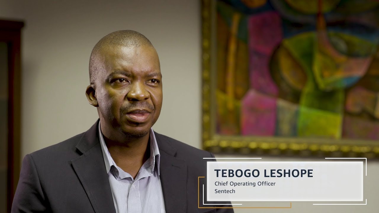 Thumbnail image of Tebogo Leshope, Chief Operating Officer at Sentech, during an interview. He is pictured indoors, dressed in a suit, with an abstract painting in the background.