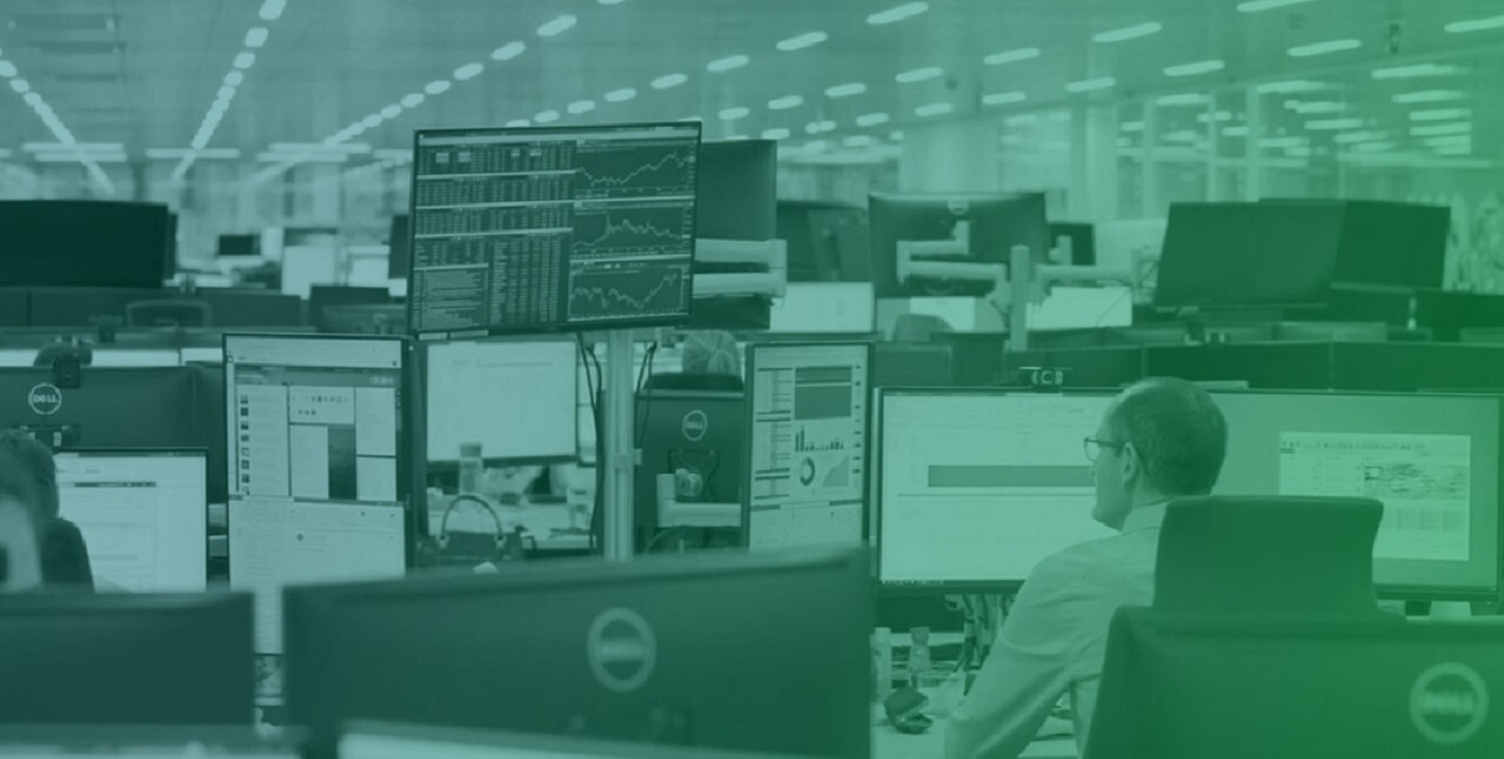 An office environment in the energy and utilities sector with personnel monitoring multiple data screens displaying real-time analytics, charts, and operational dashboards.
