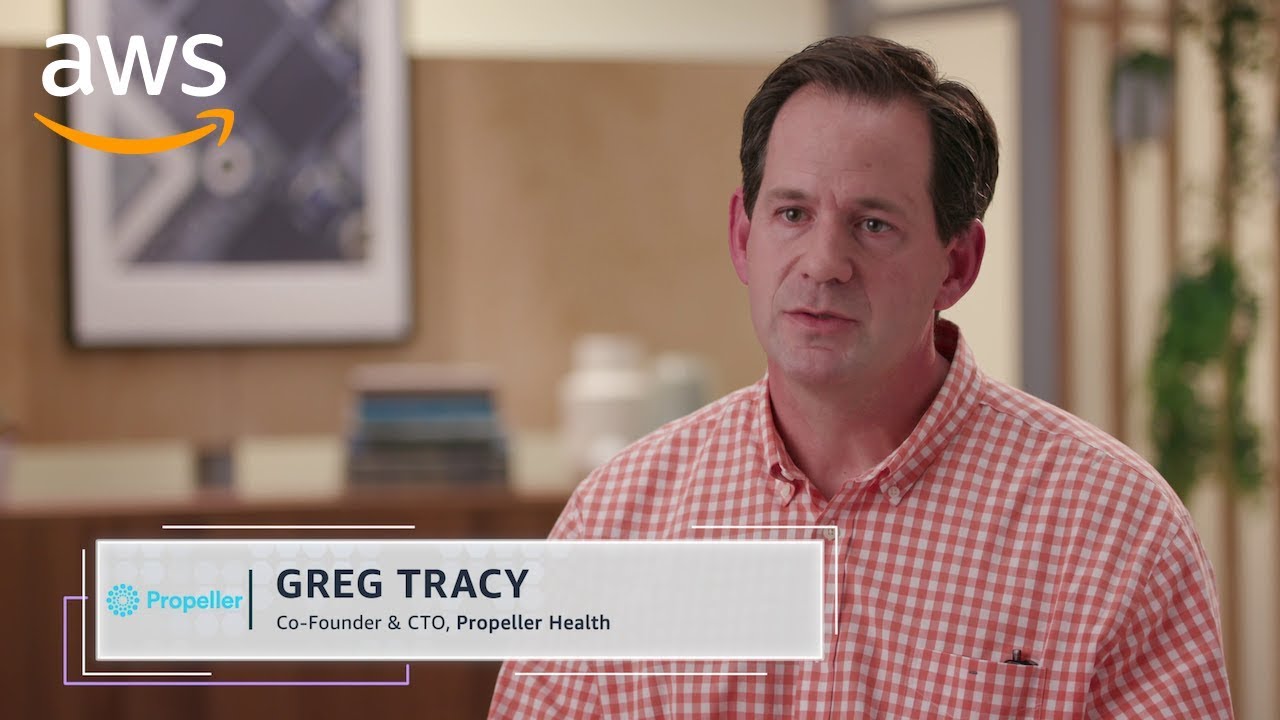 YouTube thumbnail showing Greg Tracy, Co-Founder & CTO of Propeller Health, during an interview with AWS. Greg is seated in a modern office setting, and the AWS logo is visible in the corner.