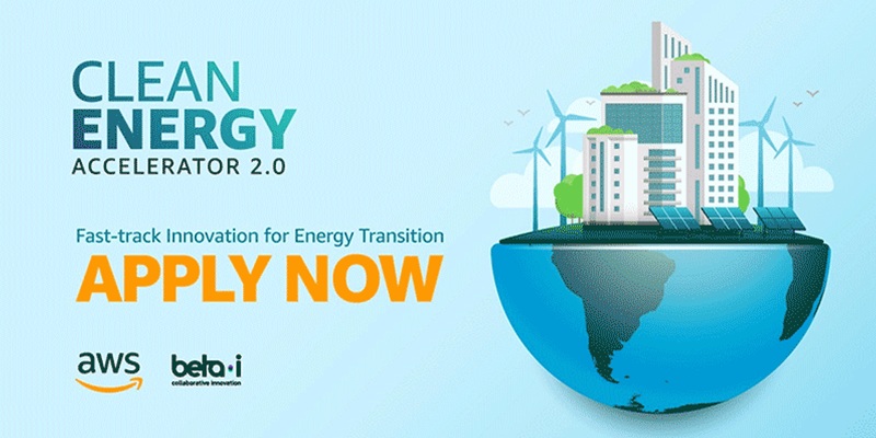 Promotional image for the Clean Energy Accelerator 2.0, featuring buildings with solar panels, wind turbines, and a globe, encouraging fast-track innovation for energy transition with the message 'Apply Now'. Includes AWS and Beta-i logos.