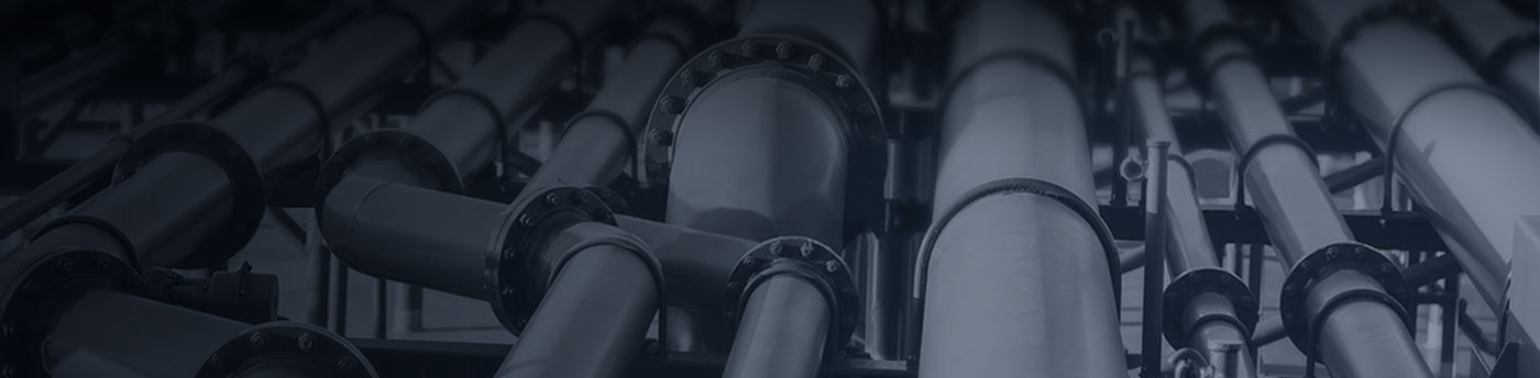 A close-up view of industrial oil and gas midstream pipeline infrastructure, showing multiple large interconnected pipes.