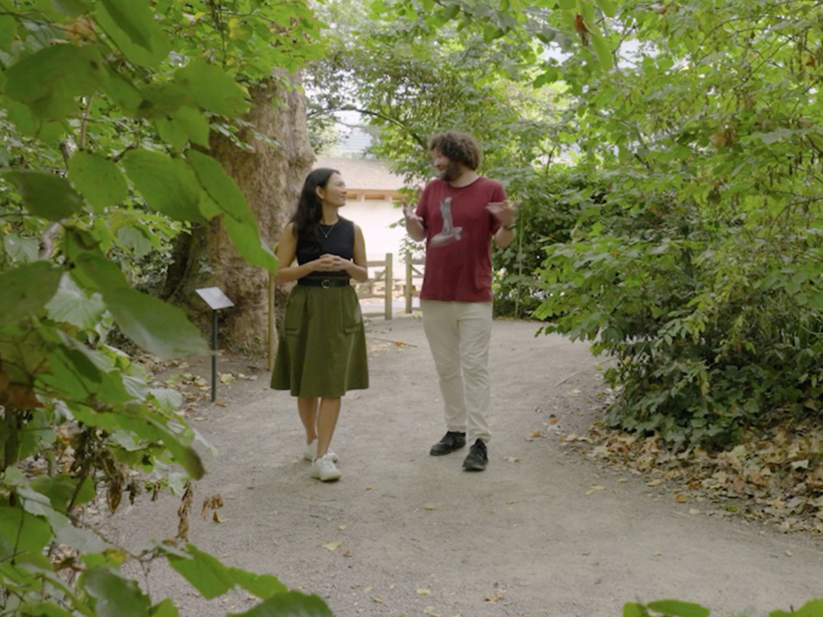 Two people walking and talking in a lush garden setting, demonstrating a sensor network in a natural outdoor environment.