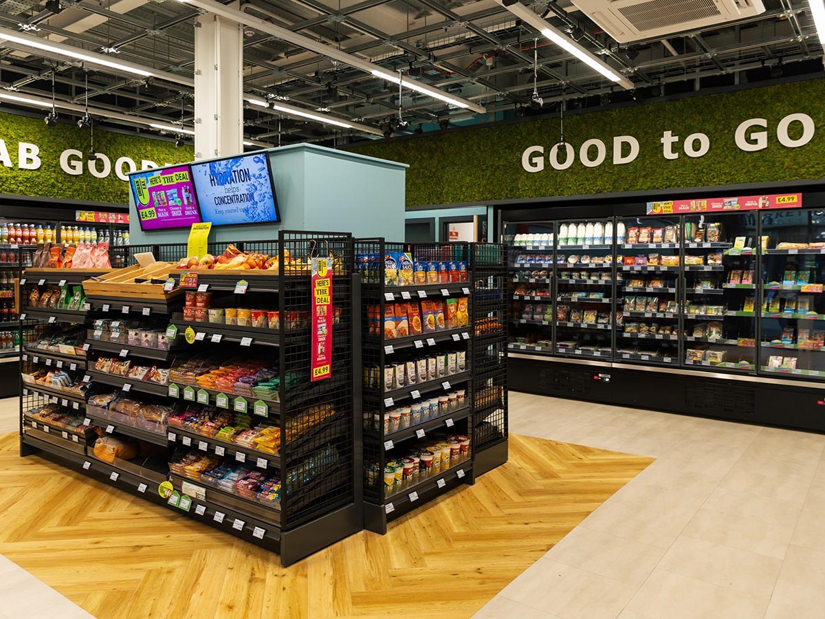 Interior view of a grab and go convenience store featuring shelves stocked with snacks and refrigerated goods, showcasing Just Walk Out technology for a seamless shopping experience.