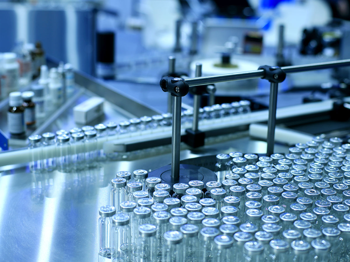 Rows of glass vials on a production line in a pharmaceutical manufacturing facility.