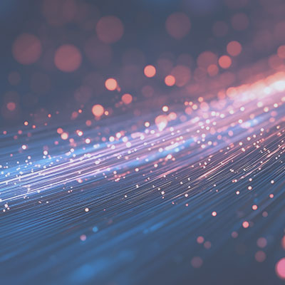 Abstract image of glowing pink and blue light streaks resembling fiber optics against a dark background.