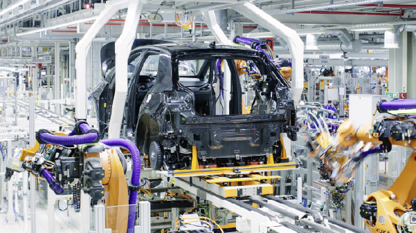 A modern automotive factory featuring advanced robotic arms assembling a car chassis on a production line. The image highlights automation and technology in the automotive manufacturing industry.