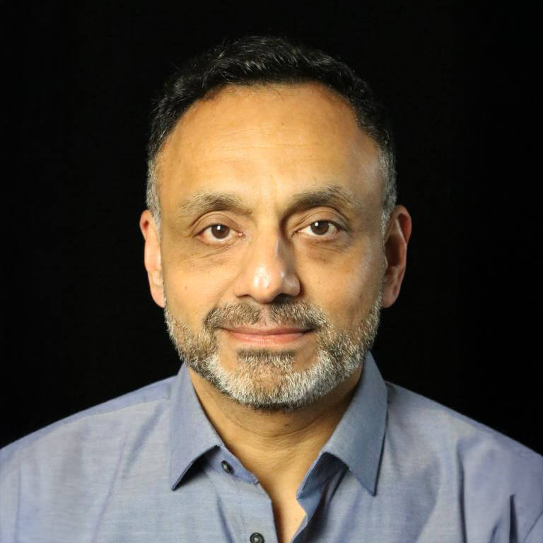 Portrait of a man in a blue shirt with a beard against a black background
