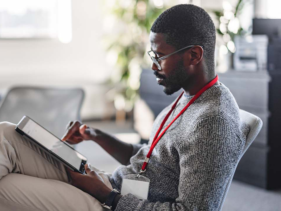 A man sitting in an office environment using a tablet device.