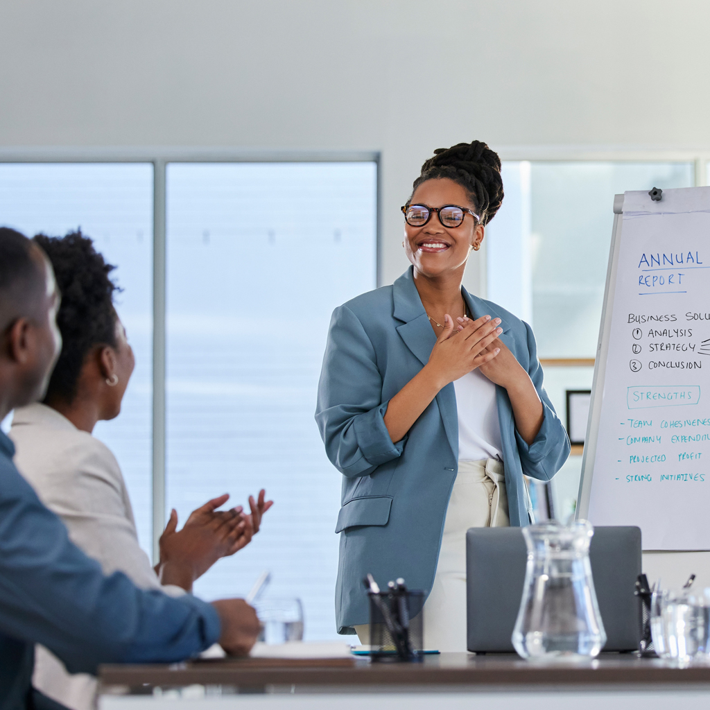 A professional presentation setting with a flip chart labeled "Annual Report" and two people seated, clapping in response.