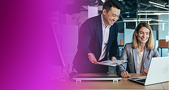 Two professionals collaborating in a modern office environment, working together at a desk with a laptop. The image represents teamwork, agility, and innovation, relating to AWS microservices and modern applications.