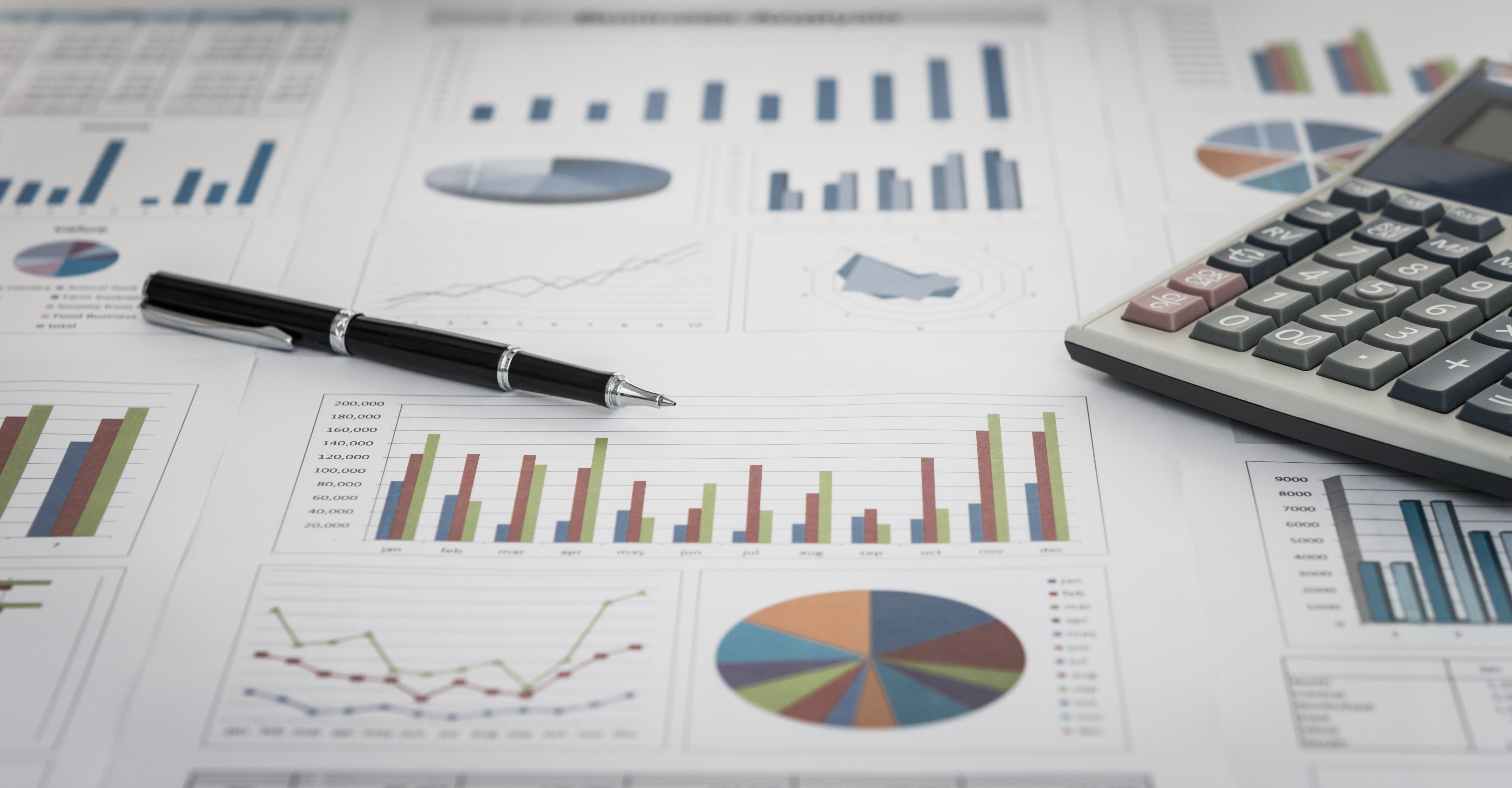 financial graph and chart report with pen, calculator on desk of financial advisor.