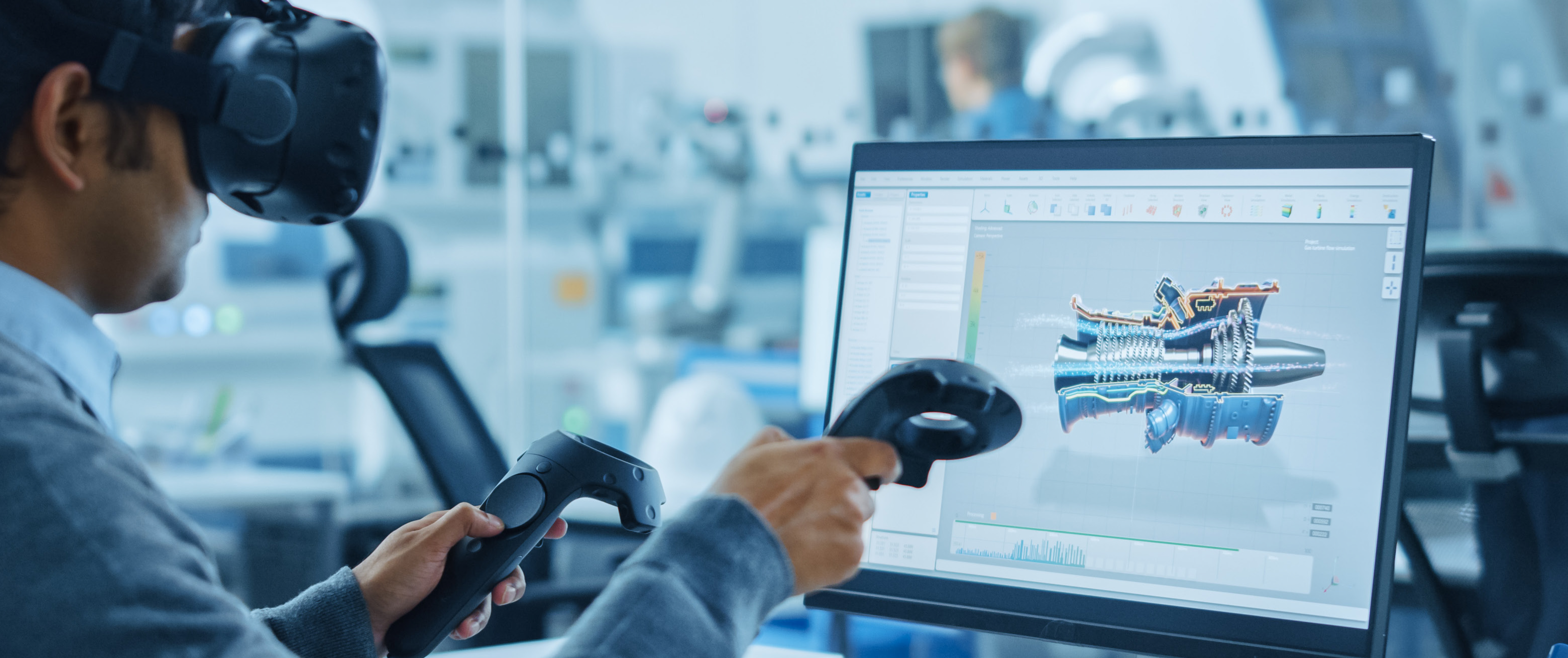 An engineer wearing a virtual reality headset and using motion controllers to interact with a 3D engine model displayed on a computer screen for design and simulation in a high-tech workspace.