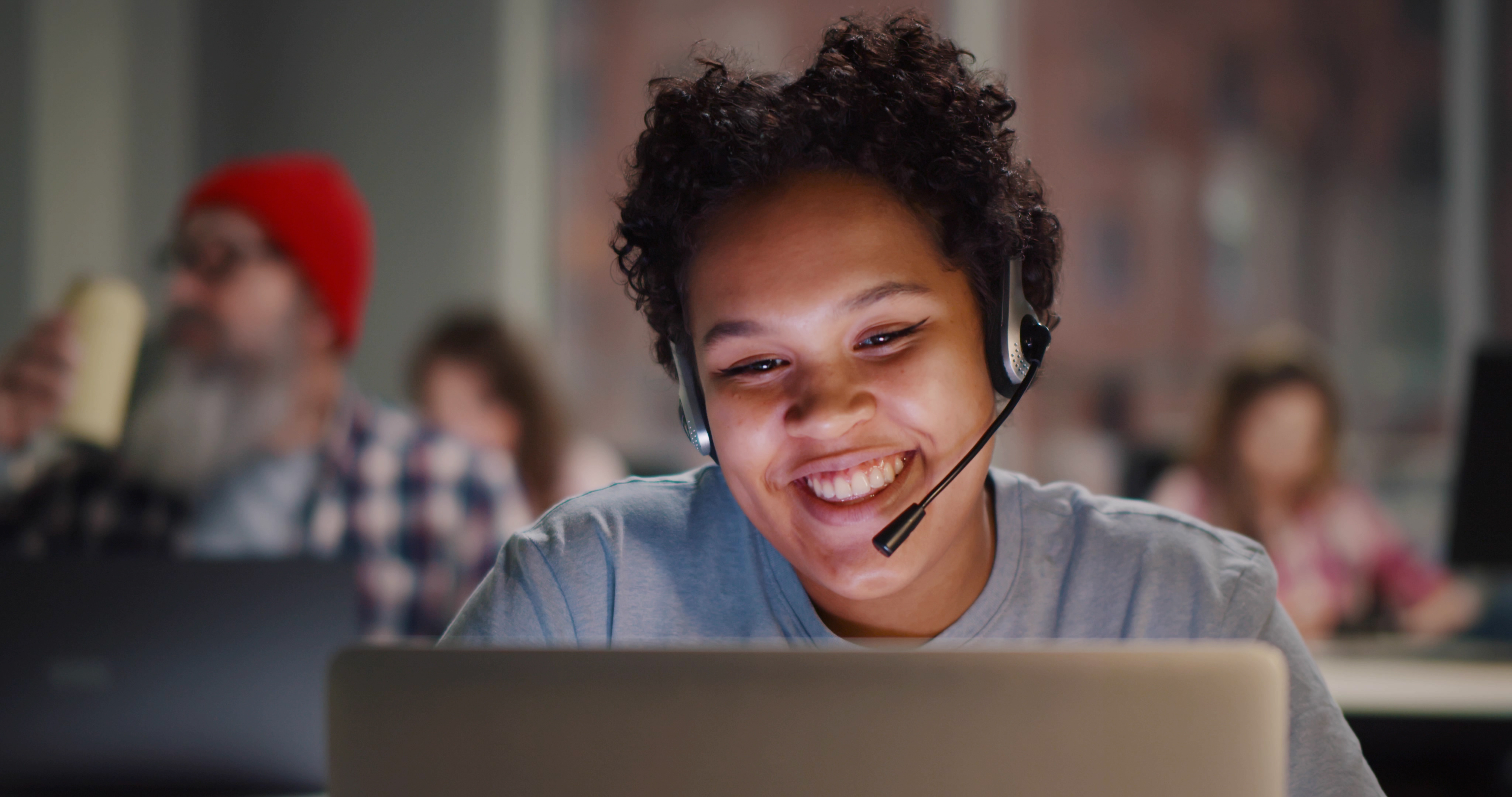 Call center agent with headset working on support hotline in modern office. Portrait of african woman agent in conversation with customer over headset sitting at desk